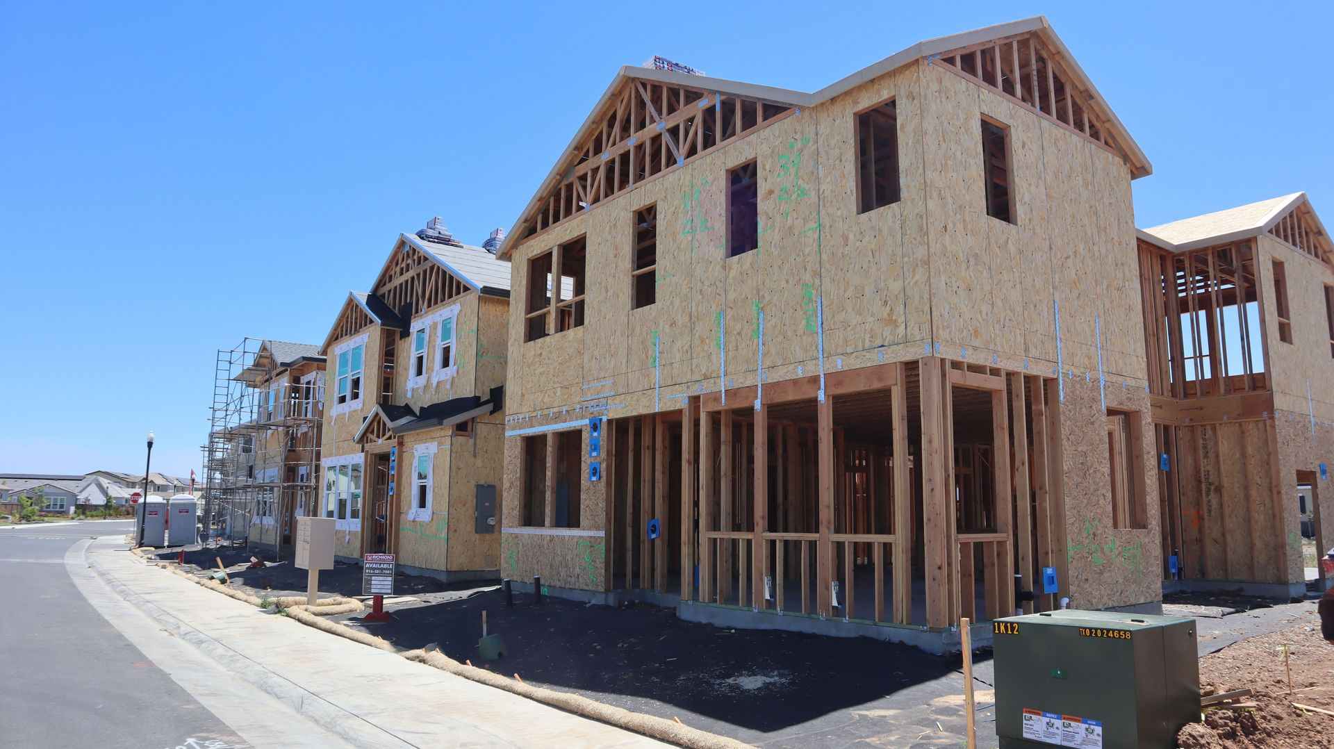 Wood-framed houses under construction on a sunny day in Elk Grove, California.